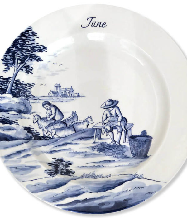 Blue and white modern Delftware plate with a man shearing a sheep near a youthful shepherd and his flock