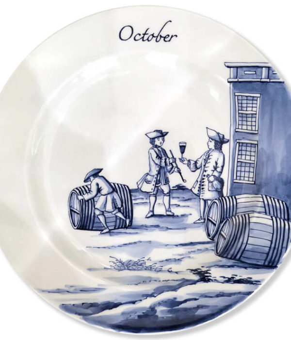 Modern blue and white Delftware plate with a man rolling a wine barrel near two gentleman, one holding a bottle and offering the other a goblet of wine