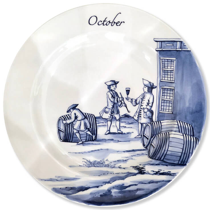 Modern blue and white Delftware plate with a man rolling a wine barrel near two gentleman, one holding a bottle and offering the other a goblet of wine