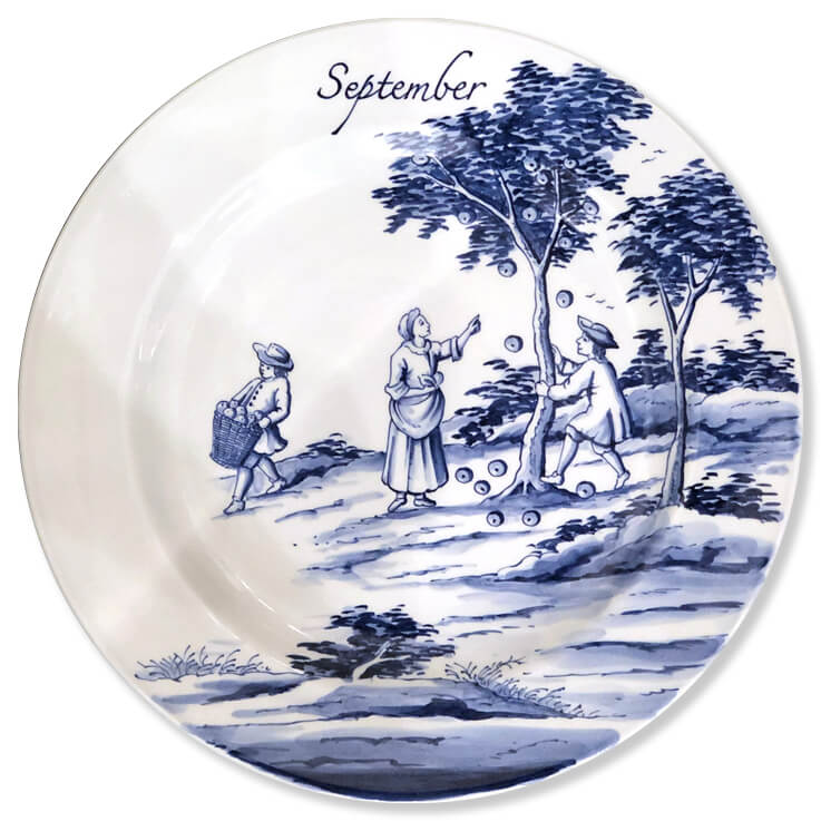 Blue And White Modern Delftware Plate With A Woman Pointing At The Apples Falling From A Tree Being Shaken By A Man While Another Man Carries Away A Basket Full Of The Fruit